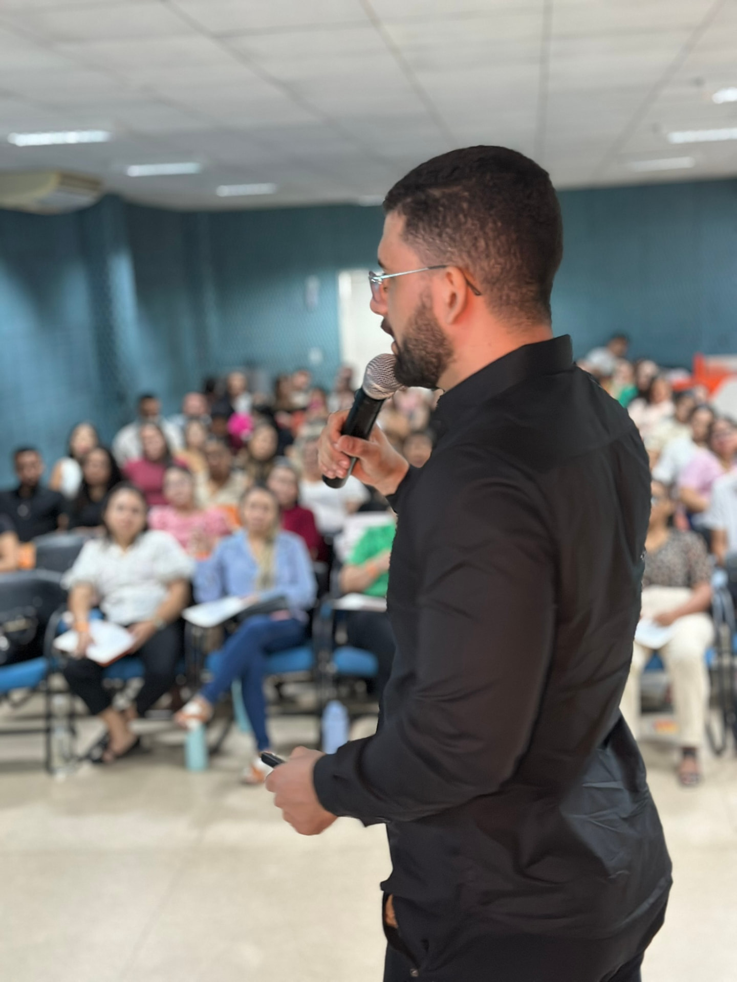 Professor conduzindo palestra com microfone diante de plateia lotada no Emergency Day